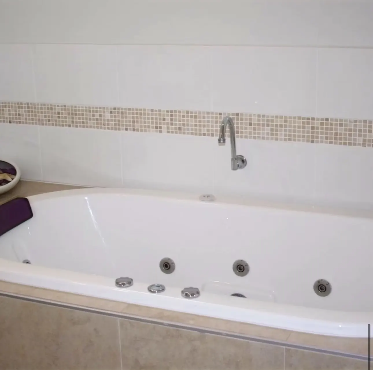 Deep spa bath with mosaic tiling in the powder room