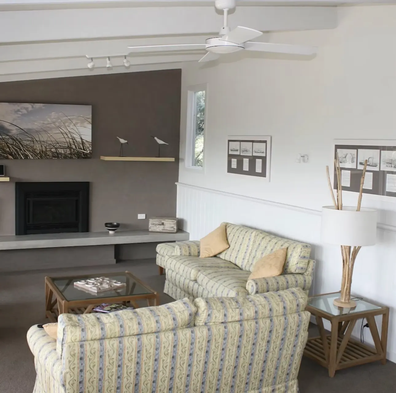 Living room with gas log fire, ceiling fan and coastal artwork at The Waterfront Loch Sport