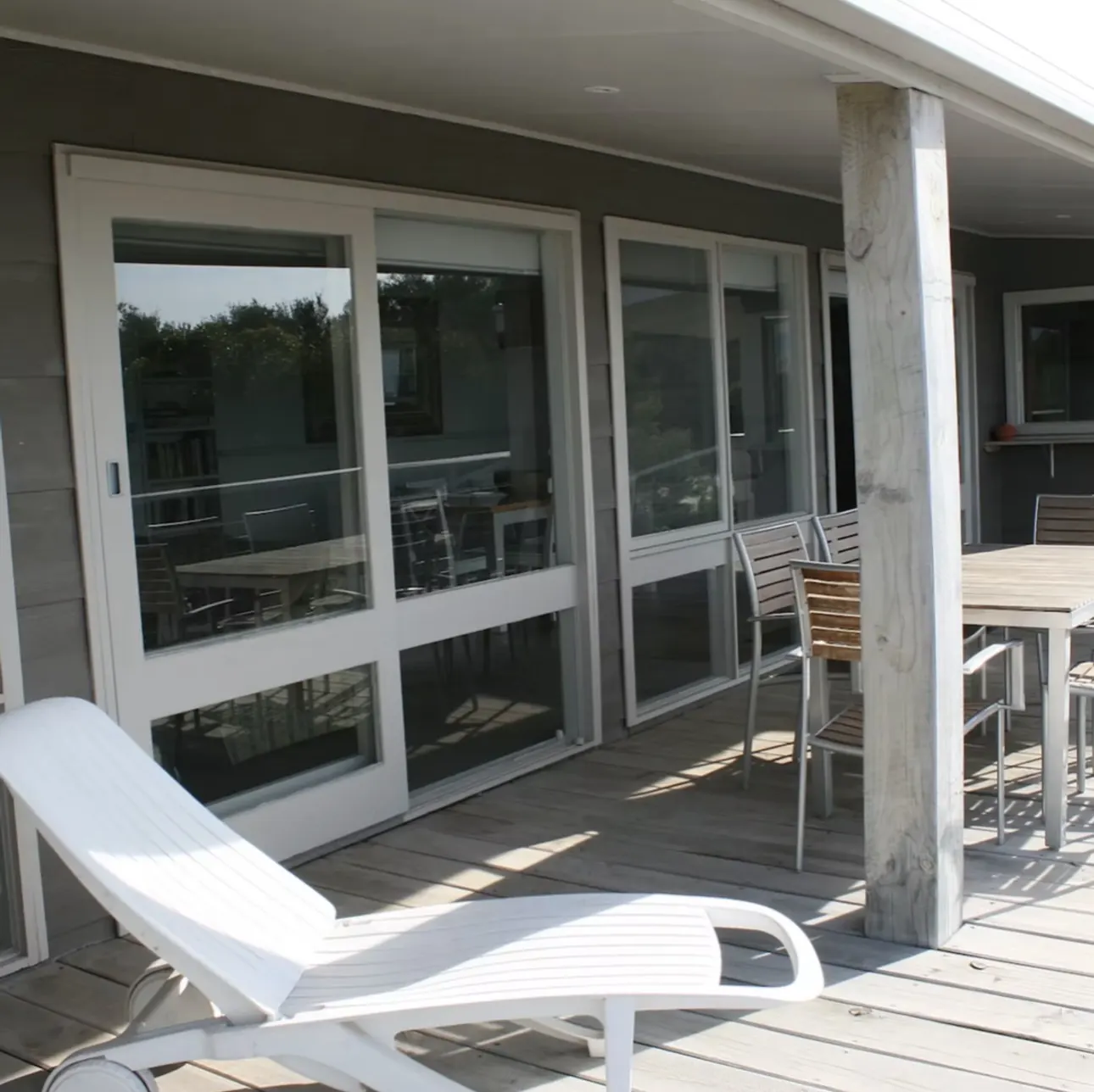Outdoor dining table and sun lounge on the north-facing deck at The Waterfront Loch Sport