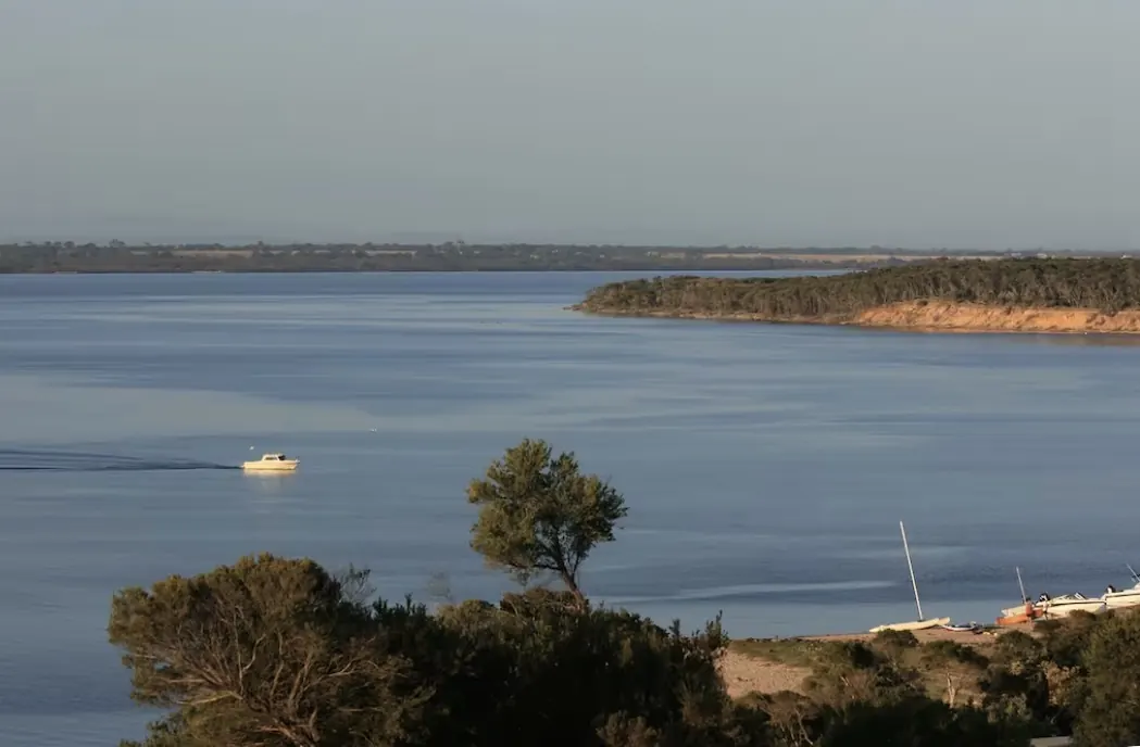 Boat cruising across Lake Victoria in evening light, seen from The Waterfront Loch Sport