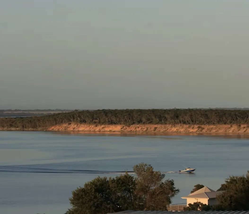 Golden light on the sandy cliffs across Lake Victoria with a boat passing by