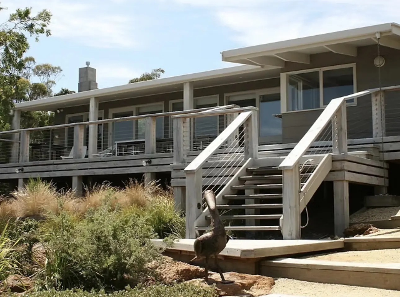 The Waterfront Loch Sport holiday house with its long timber deck and coastal garden