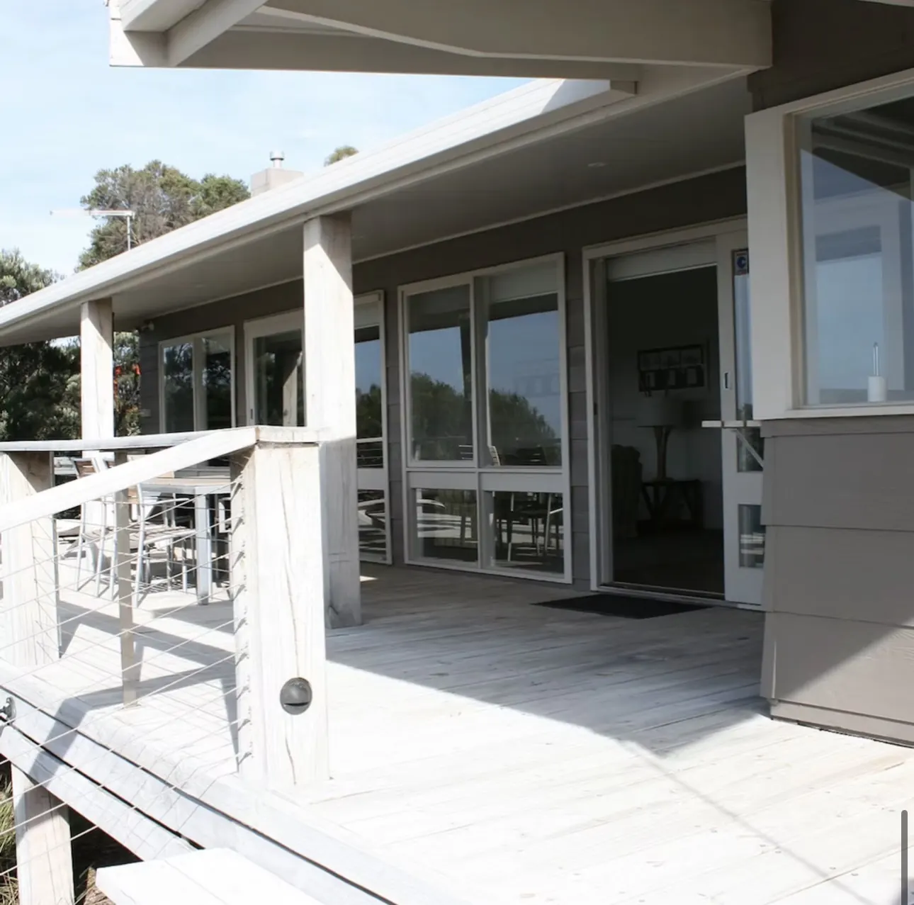 Sunlit timber deck and sliding doors at the front of The Waterfront Loch Sport